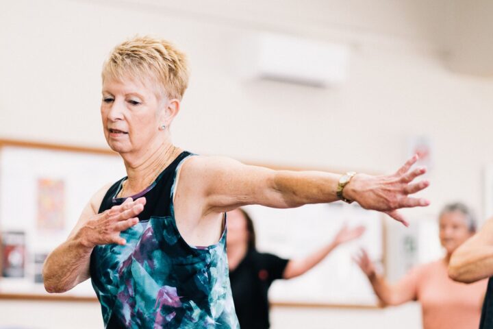 Woman over 60 practicing balance exercises in a group fitness class to prevent falls