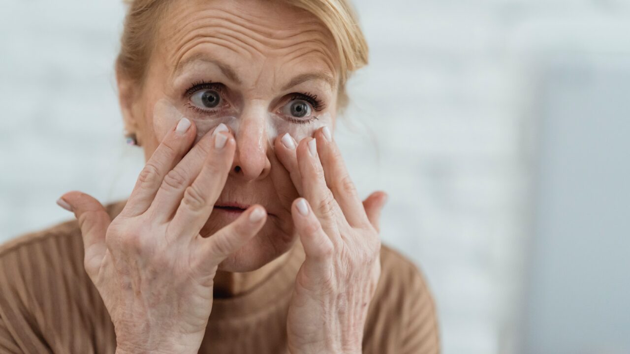 Mature woman applying eye cream as part of a skincare routine for aging skin