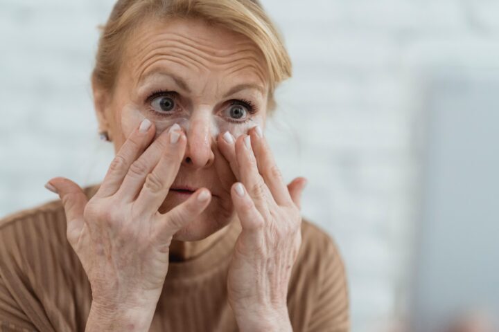 Mature woman applying eye cream as part of a skincare routine for aging skin