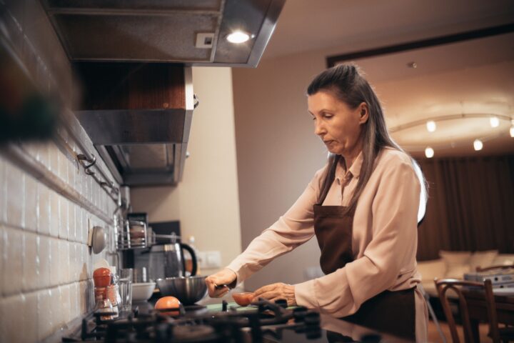 Woman over 40 cooking a healthy meal at home to support a stable metabolism