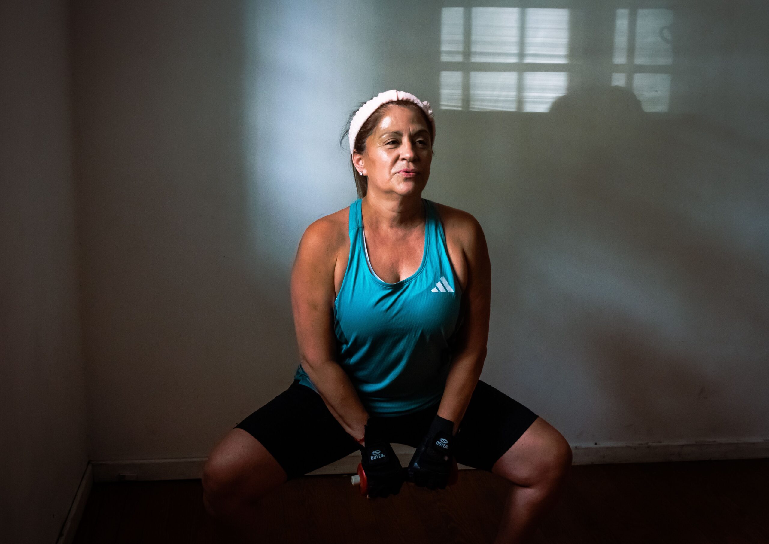 Mature woman doing resistance exercise with dumbbells indoors
