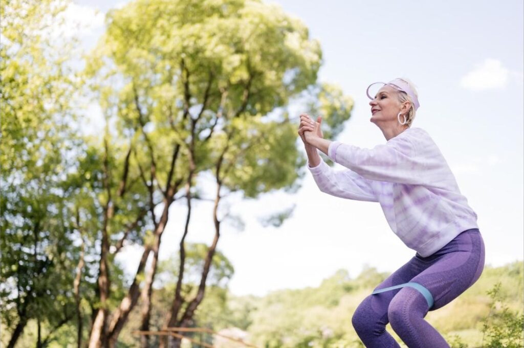Senior woman using a resistance band for strength training outdoors