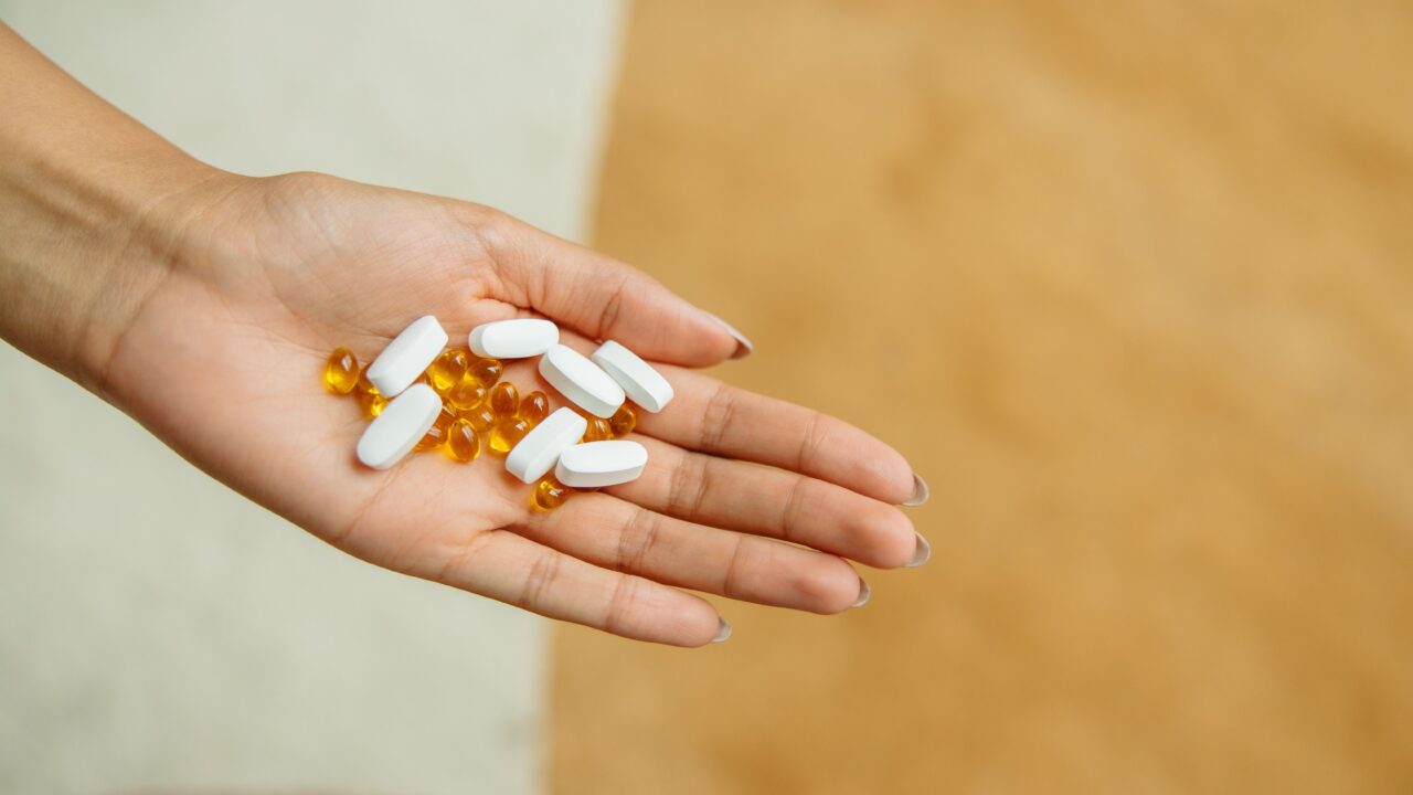 Hand holding supplement capsules, representing popular but often unproven anti-aging products