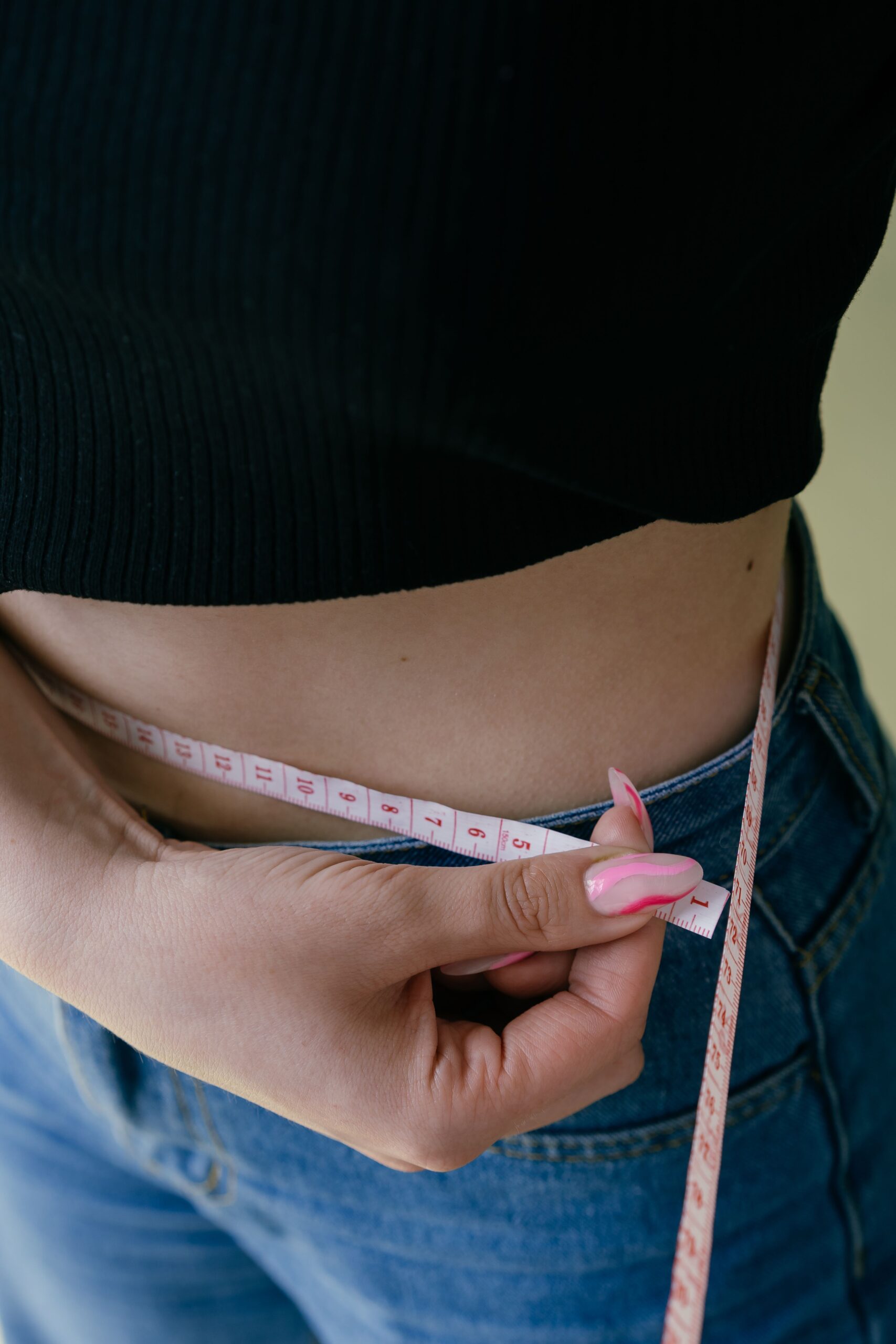 Woman measuring her waist circumference, a practical marker of visceral fat-related health risk